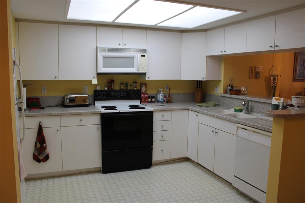 9722 Indian Key Trail, Unit 116 Seminole, FL 33776 - Photo 10 of 65 a kitchen with white cabinets and appliances