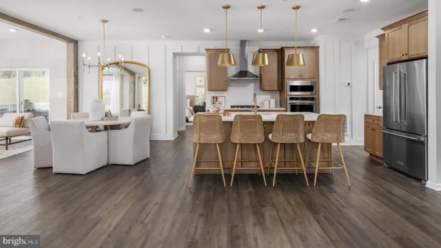 a dining room with furniture wooden floor kitchen view and a refrigerator