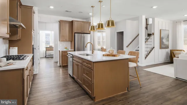 a kitchen with stainless steel appliances kitchen island granite countertop a stove a sink a refrigerator and a island with wooden floor