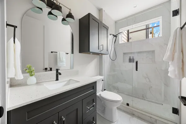 a bathroom with a granite countertop sink a toilet and shower