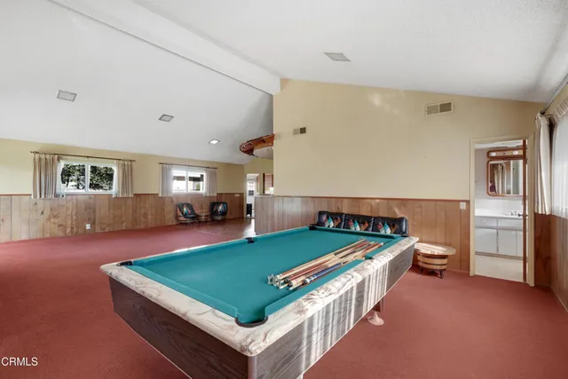 a living room with furniture pool table and windows