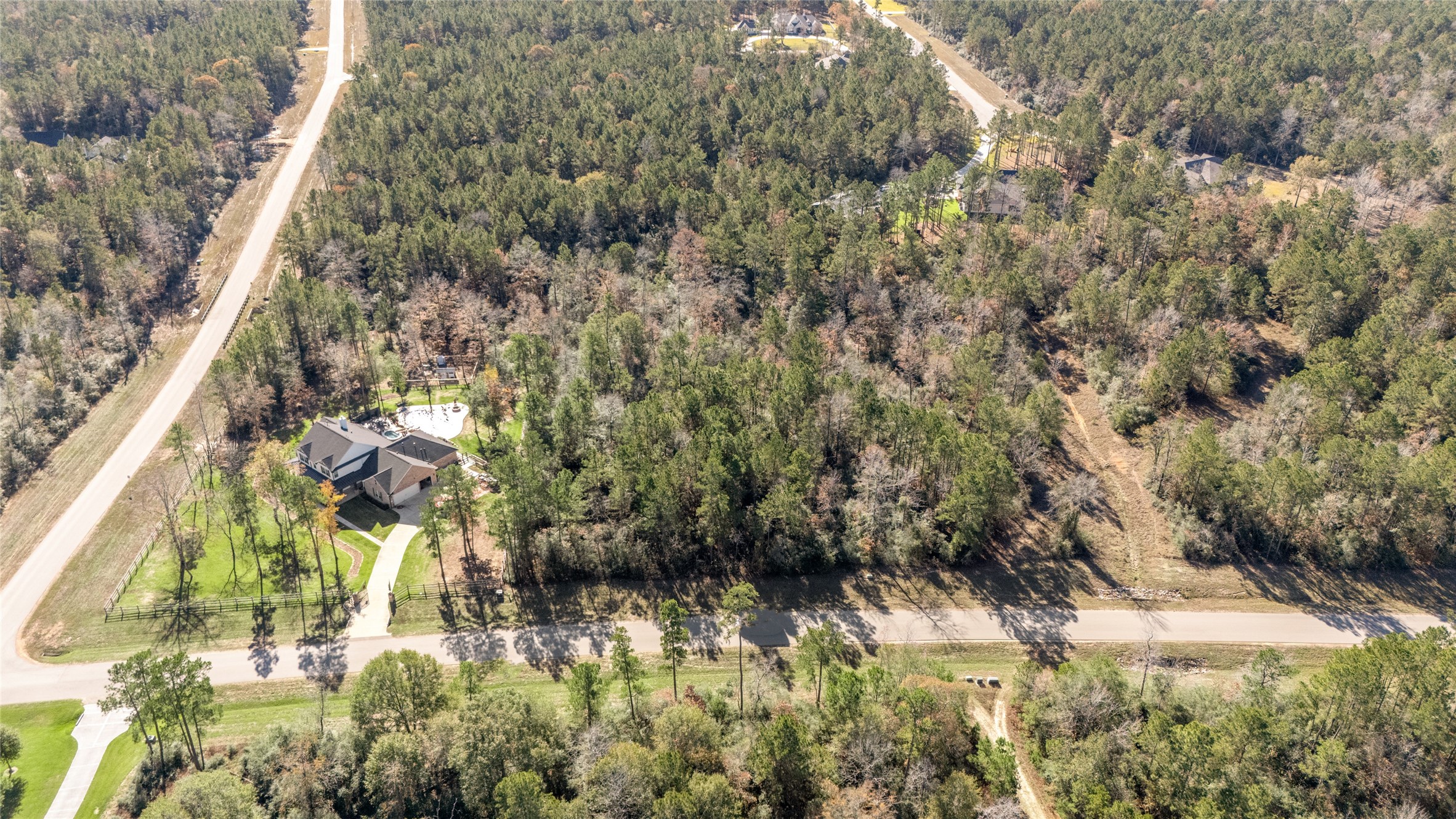 10674 Ruger Road Willis, TX 77378 - Photo 5 of 15 Aerial view illustrating a neighboring custom home on one side of the property along with paved access roads.