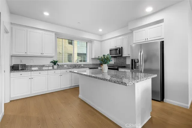 a kitchen with kitchen island granite countertop a stove a sink a oven a dining table and chairs