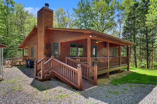 a view of a house with a yard and deck area under a large tree