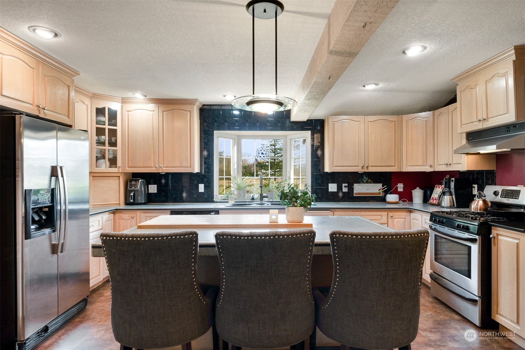 3941 Loomis Trail Road Blaine, WA 98230 - Photo 13 of 40 a kitchen with stainless steel appliances granite countertop a stove a refrigerator a sink dishwasher a dining table and chairs with wooden floor