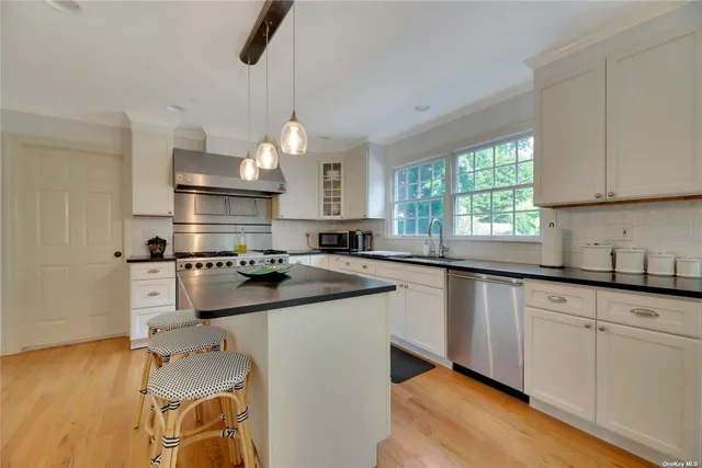 a kitchen with stainless steel appliances granite countertop a sink window and cabinets