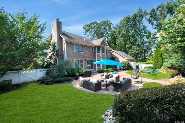 a backyard of a house with table and chairs under an umbrella