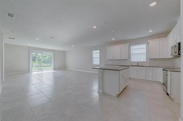 a large white kitchen with a refrigerator a sink and a stove top oven