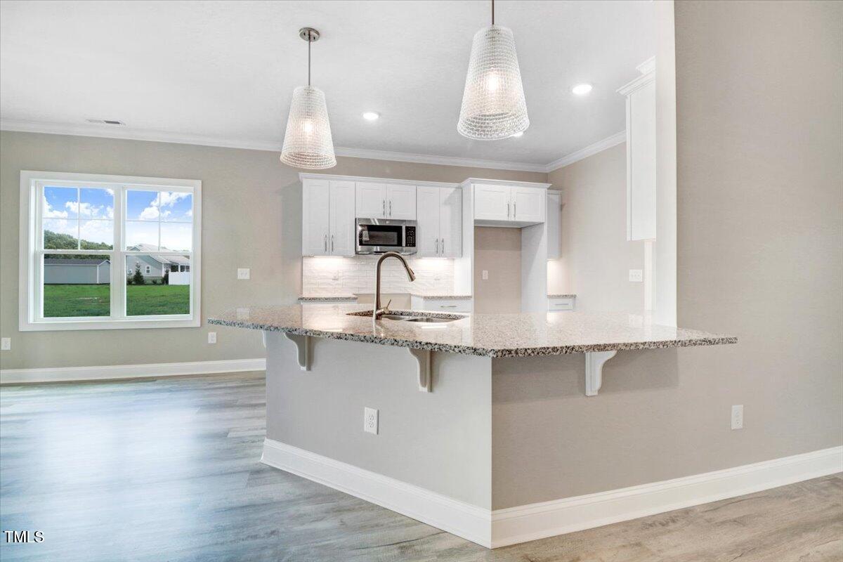 9550 Bear Run Lane Middlesex, NC 27557 - Photo 13 of 32 a kitchen with kitchen island granite countertop a sink cabinets and wooden floor