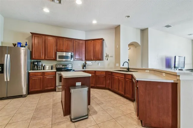 a kitchen with stainless steel appliances granite countertop wooden cabinets a sink a stove a refrigerator and a microwave