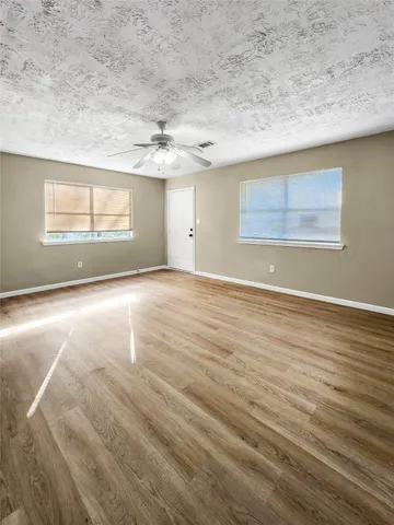 an empty room with wooden floor and windows