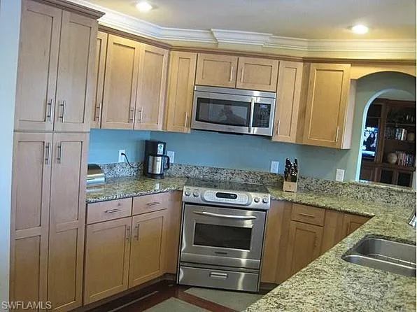 a kitchen with granite countertop a sink stove and microwave