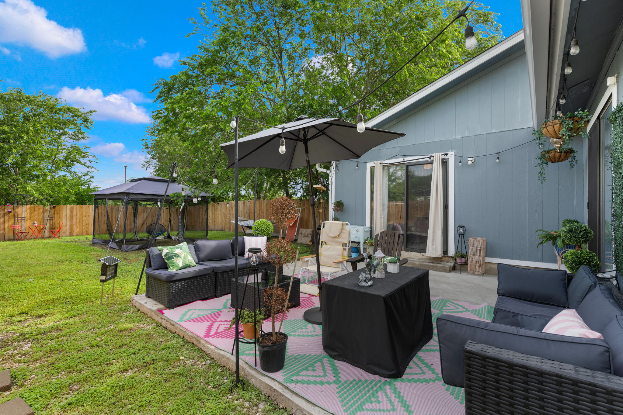 8317 Forest Ridge Drive San Antonio, TX 78239 - Photo 19 of 26 A private backyard oasis with an inviting patio, lush green lawn, and string lights, perfect for outdoor entertaining.