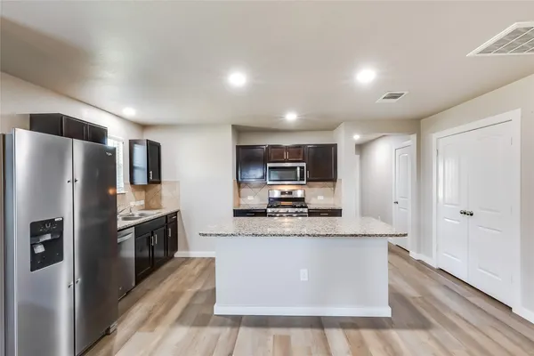 a kitchen with stainless steel appliances granite countertop a stove refrigerator and microwave