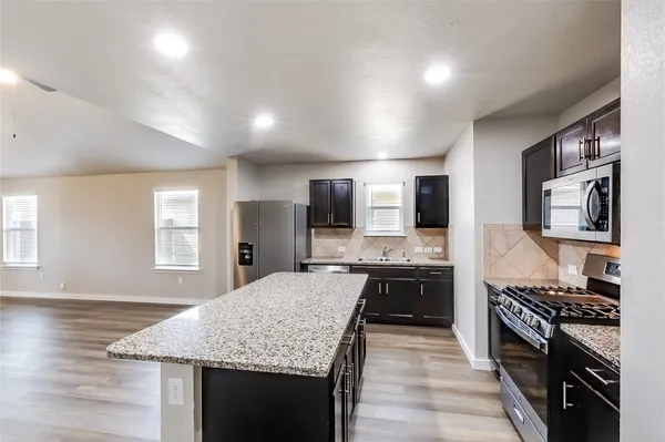a kitchen with stainless steel appliances granite countertop a sink stove microwave and refrigerator
