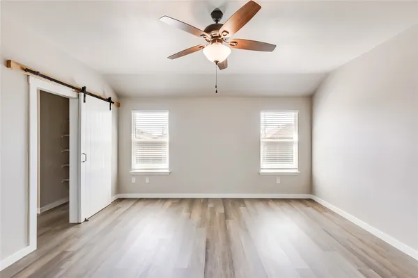 a view of empty room with wooden floor and fan
