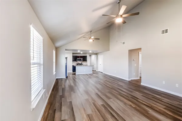 an empty room with wooden floor cabinet and windows