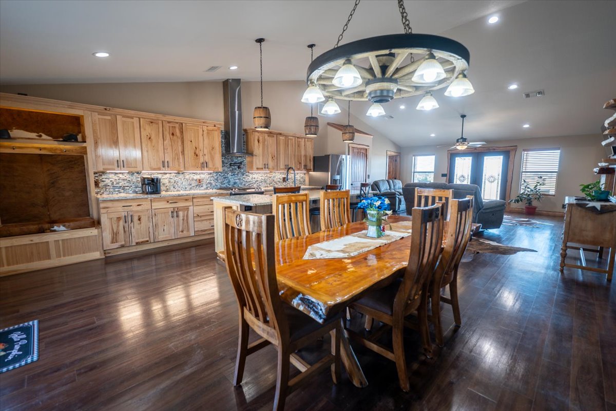 Dining space with vaulted ceiling, dark wood-style floors, recessed lighting, and a ceiling fan