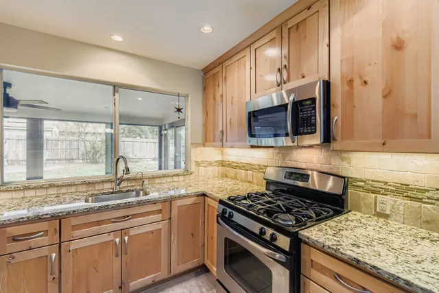 a kitchen with stainless steel appliances granite countertop a stove a sink and a microwave