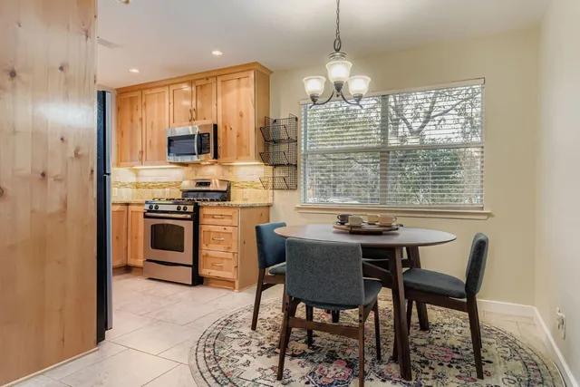 a kitchen with stainless steel appliances granite countertop a stove a sink a microwave a dining table and chairs