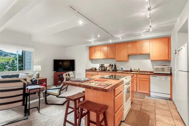 a kitchen with stainless steel appliances granite countertop a stove top oven a sink dishwasher a dining table and chairs with wooden floor