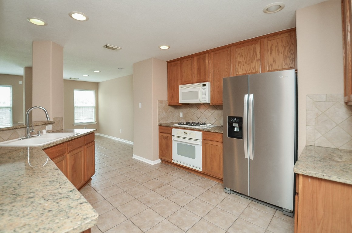 7134 Winston Ranch Parkway Richmond, TX 77406 - Photo 12 of 32 a kitchen with stainless steel appliances granite countertop a refrigerator sink and stove