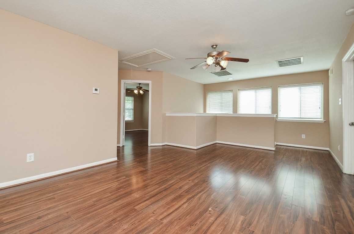 7134 Winston Ranch Parkway Richmond, TX 77406 - Photo 21 of 32 an empty room with wooden floor chandelier fan and windows