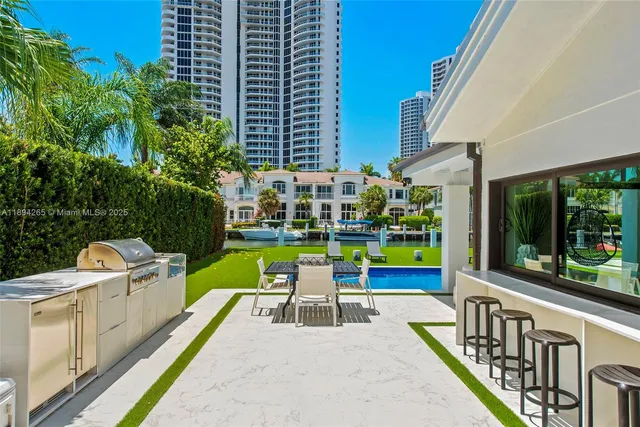 a view of a patio with couches table and chairs under an umbrella with a large tree