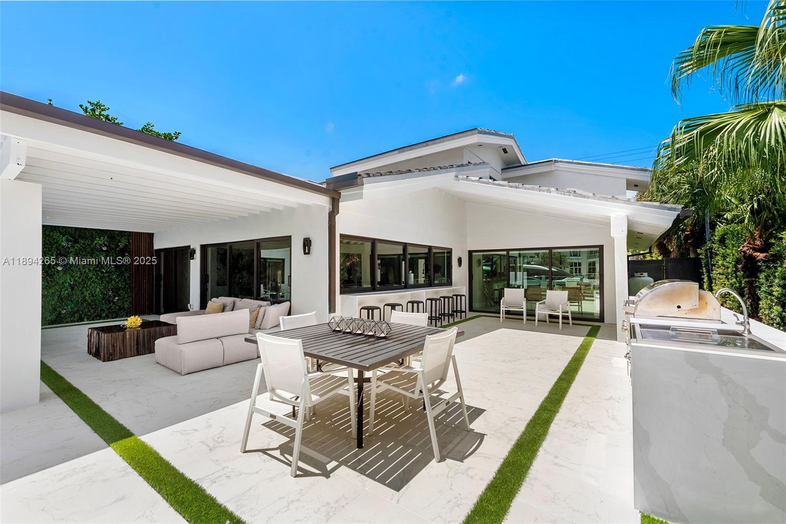 207 Holiday Drive Hallandale Beach, FL 33009 - Photo 20 of 50 a view of a patio with couches table and chairs under an umbrella with a large tree