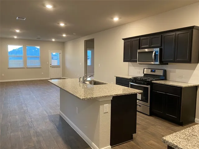 a kitchen with kitchen island stainless steel appliances a sink stove and refrigerator