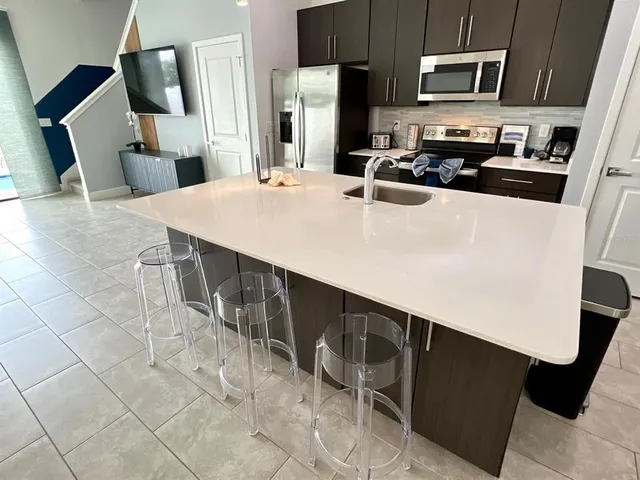 a kitchen with stainless steel appliances a stove a refrigerator a sink a counter space and cabinets