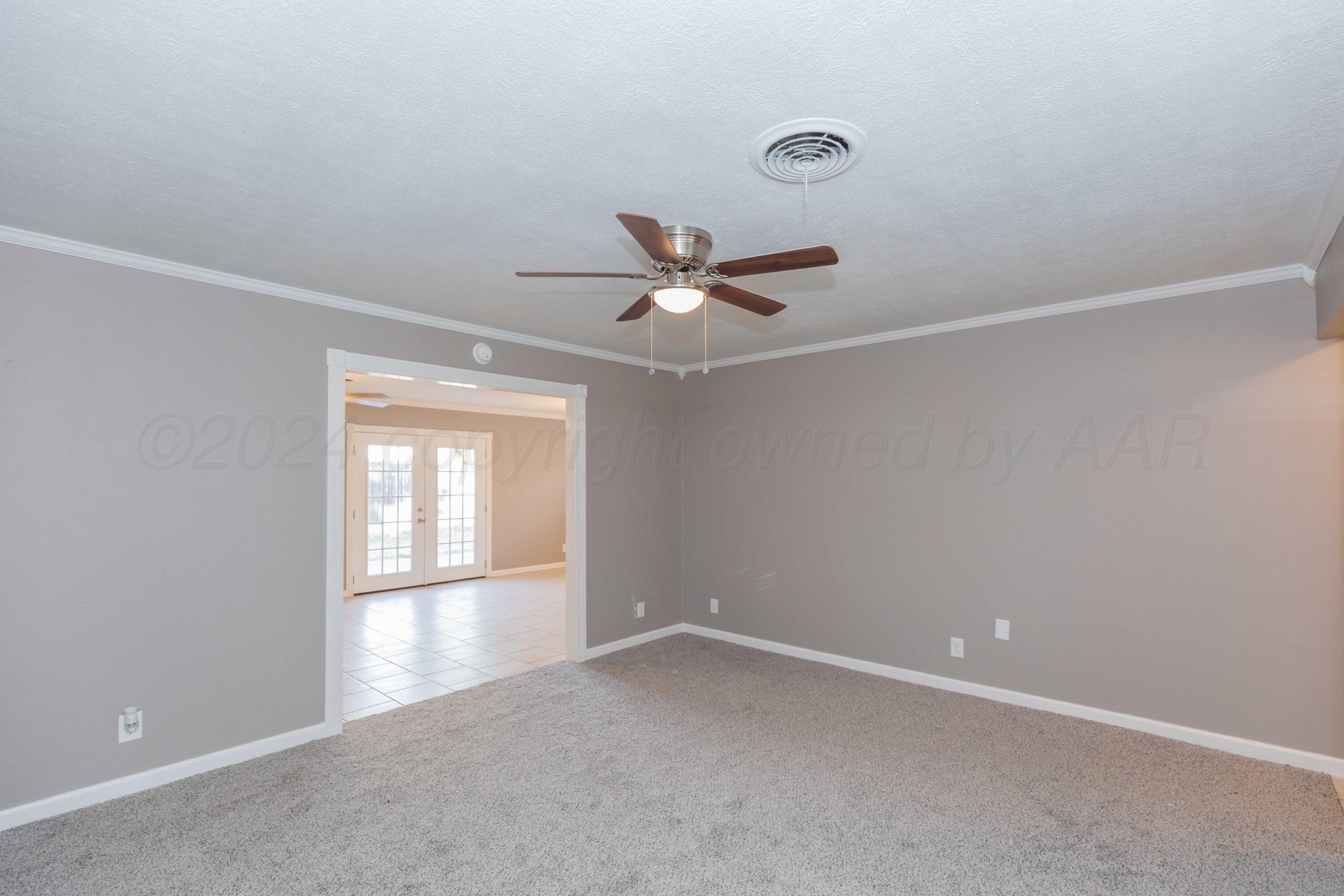 402 Beech Street Borger, TX 79007 - Photo 5 of 41 an empty room with a window and a ceiling fan