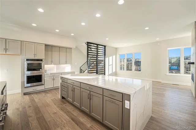 a kitchen with stainless steel appliances granite countertop a sink and wooden floors