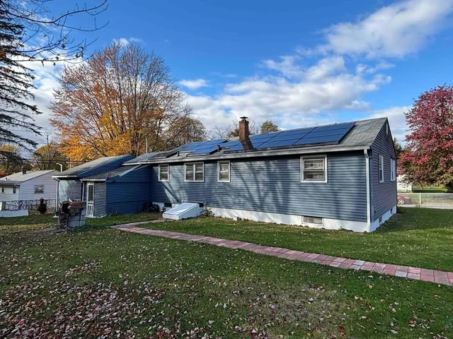 a view of a yard in front of a house with plants and large tree
