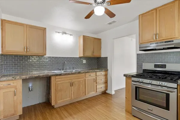 a kitchen with granite countertop cabinets stainless steel appliances and wooden floor