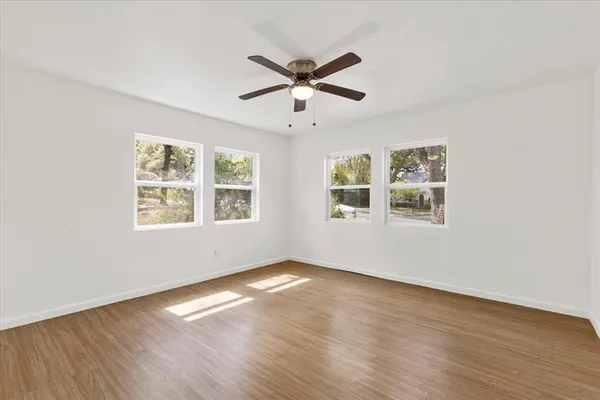 a view of an empty room with wooden floor and a window