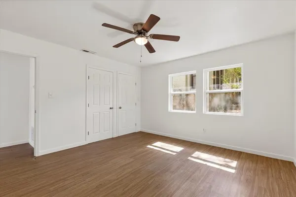 a view of empty room with wooden floor and fan