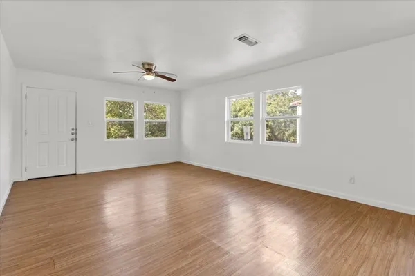 a view of an empty room with wooden floor and a window
