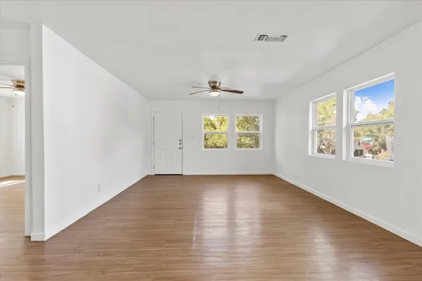 a view of an empty room with a window and wooden floor