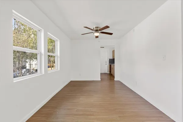 a view of an empty room with a window and wooden floor