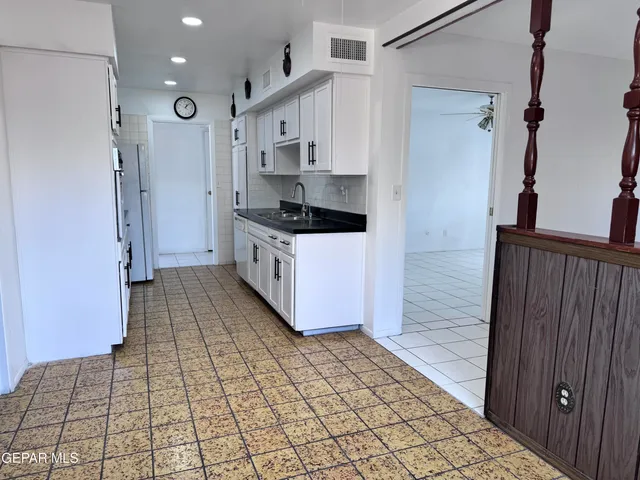 a kitchen with granite countertop a stove a sink and a refrigerator