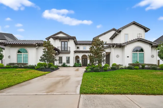 a view of white house with a big yard and potted plants