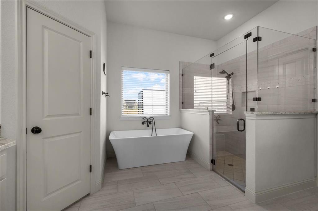 329 Palo Alto Drive Springtown, TX 76082 - Photo 17 of 34 Freestanding soaking tub with a floor-mounted fixture, accompanied by a glass-enclosed shower with a built-in bench
