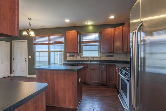 1240 Mariemont Road, Unit E Sugar Grove, IL 60554 - Photo 14 of 32 a kitchen with stainless steel appliances granite countertop a sink a stove and a refrigerator