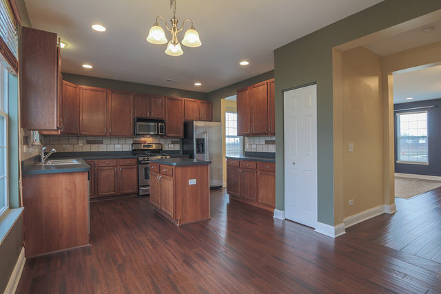 1240 Mariemont Road, Unit E Sugar Grove, IL 60554 - Photo 17 of 32 a kitchen with stainless steel appliances granite countertop wooden floors a stove a sink and a refrigerator