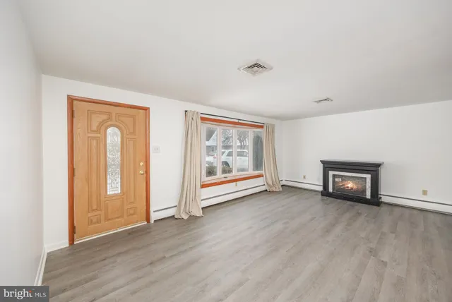 an empty room with wooden floor and window