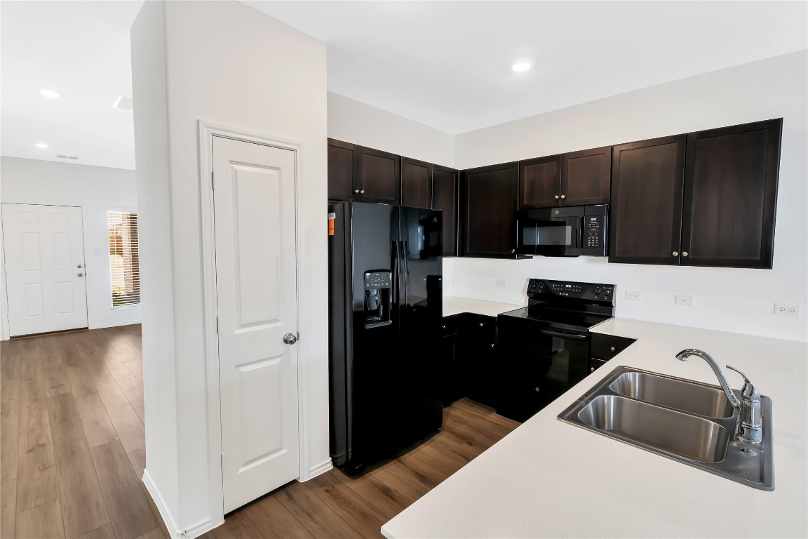 160 The Bad Way Jarrell, TX 76537 - Photo 7 of 33 Kitchen featuring black appliances, light countertops, dark brown cabinets, dark wood-style flooring, and recessed lighting
