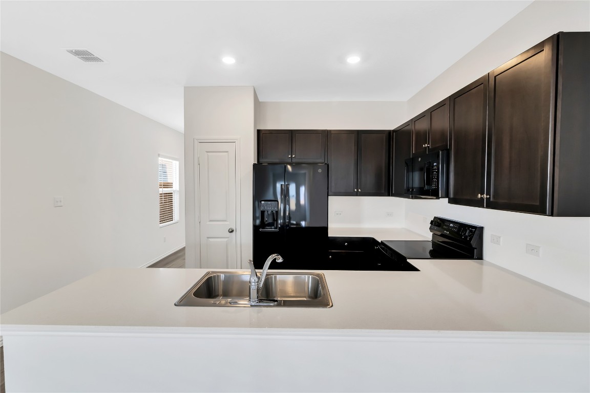 160 The Bad Way Jarrell, TX 76537 - Photo 8 of 33 Kitchen featuring a peninsula, black appliances, light countertops, dark brown cabinets, and recessed lighting