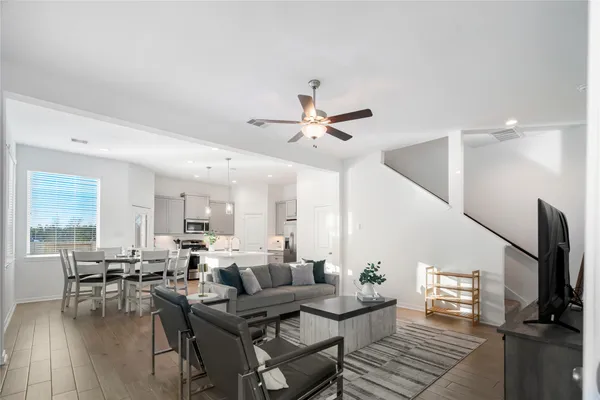 a living room with furniture kitchen view and a large window