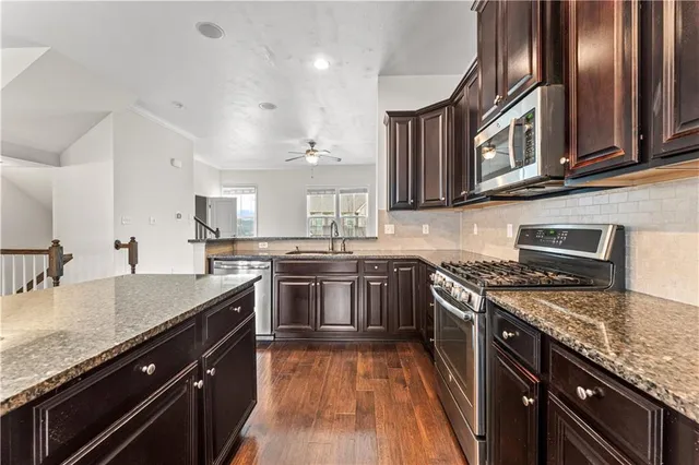 a kitchen with stainless steel appliances granite countertop a stove top oven a sink and dishwasher